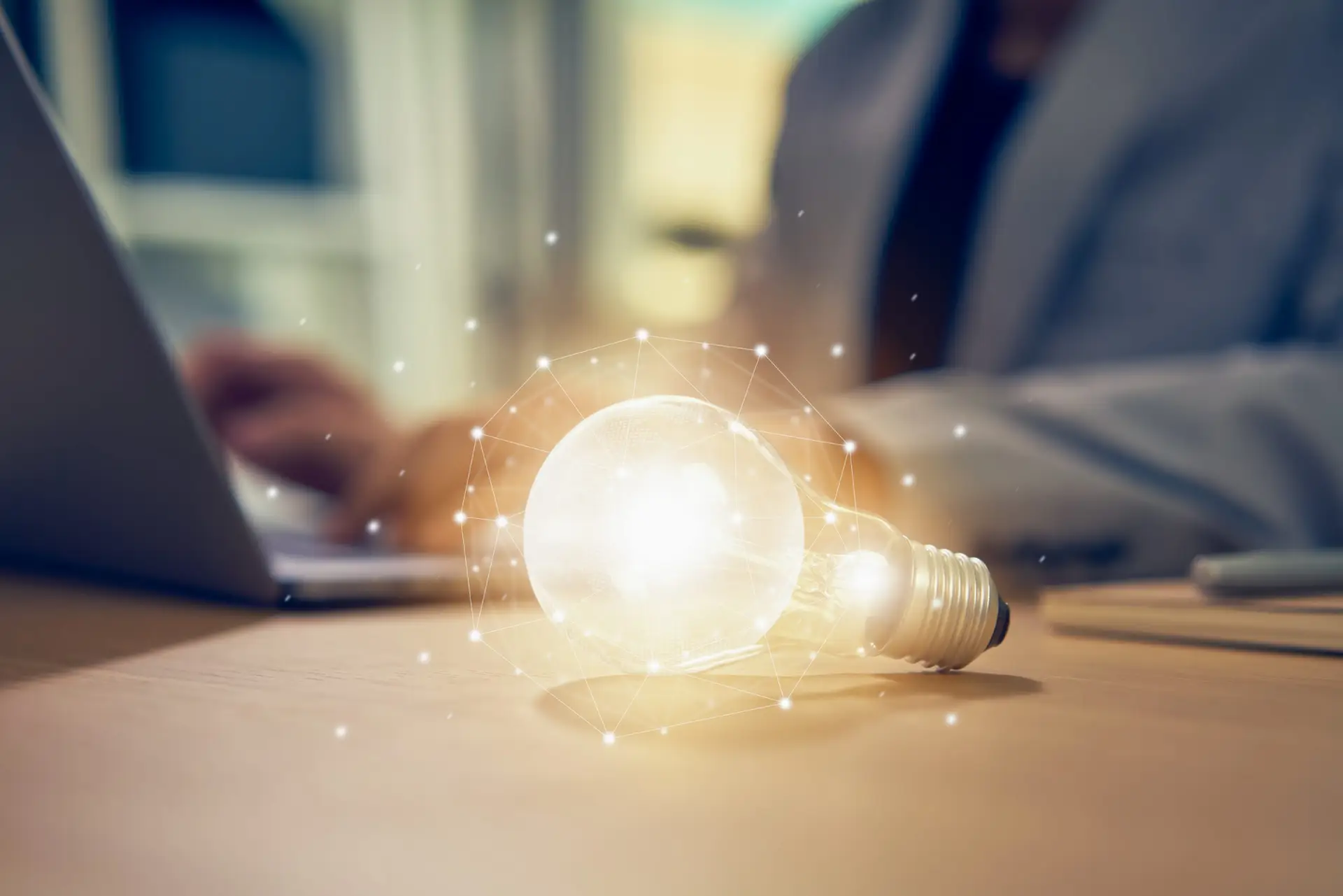 Businessman working on laptop and light bulb on the table with innovative and creativity are keys to success. Concept knowledge leads to ideas and inspiration.