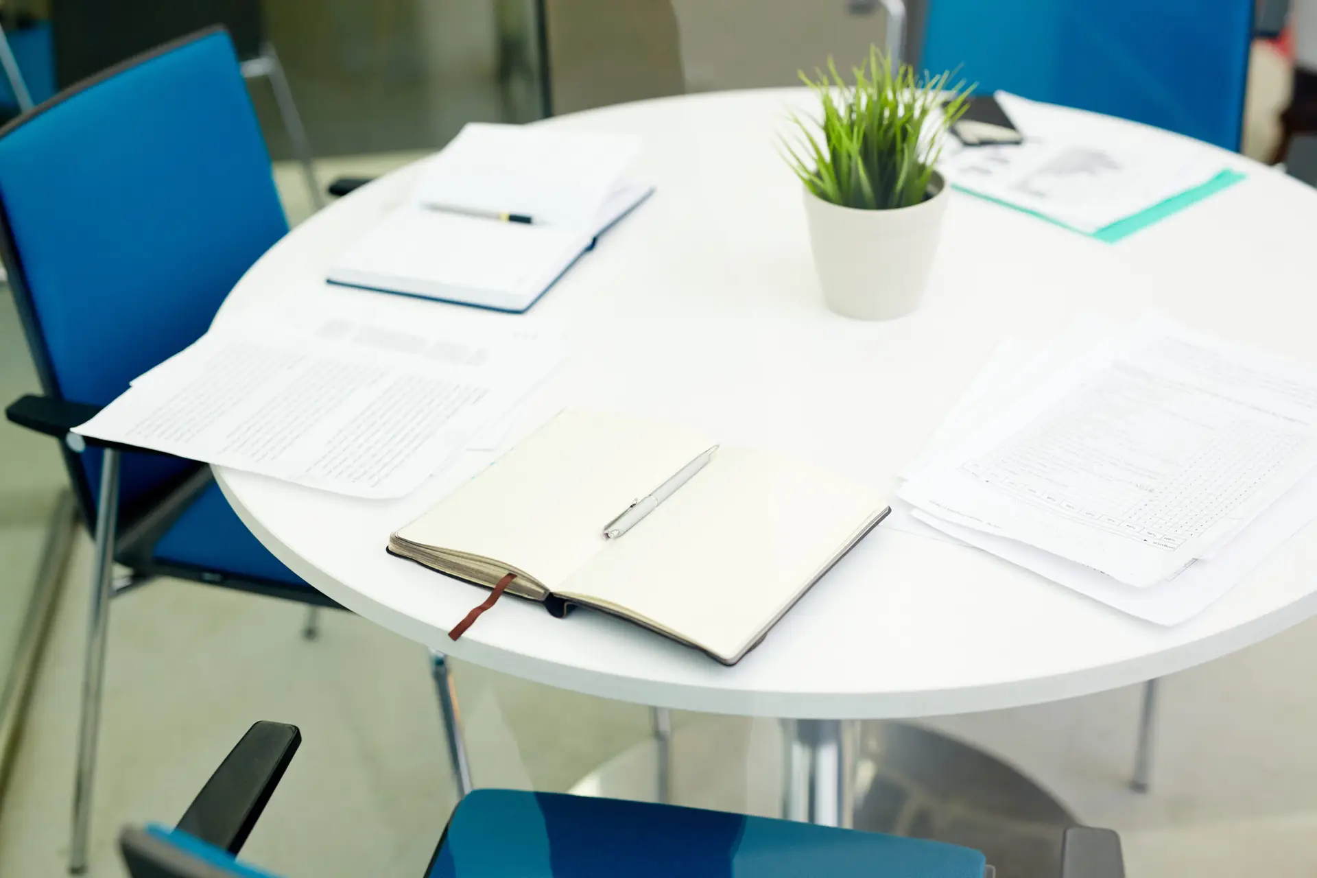 Objects for business meeting on round table with several empty chairs near by
